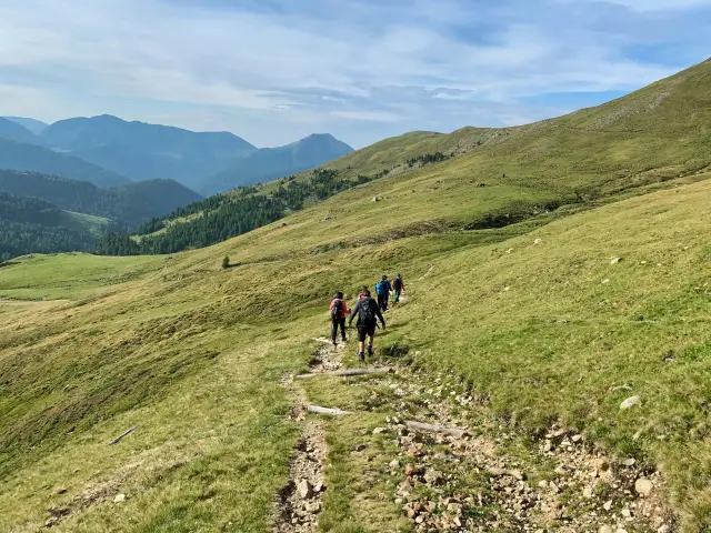 Wandergruppe auf einem Pfad durch grüne Hügel